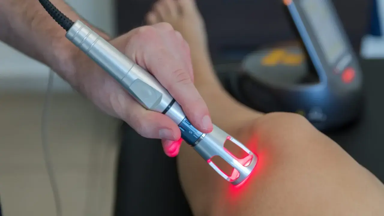 Rehabilitacja laserem na czym polega? Terapeuta aplikuje wiązkę światła na skórę pacjenta, by wspomóc regenerację tkanek i zmniejszyć ból.