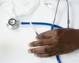 Dłoń pacjenta obok stetoskopu i strzykawki. Czy fizjoterapeuta wystawia L4?