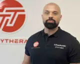 Tomasz Chachurski w czarnej koszulce z logo Toonytherapy, na tle białej ściany z logo.