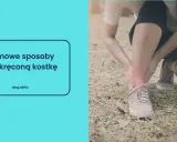 Osoba trzymająca się za czerwoną, bolącą kostkę w butach sportowych.
