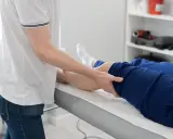 Fizjoterapeuta wykonuje zabieg na nodze pacjenta. Fizjoterapia ambulatoryjna co to znaczy? To leczenie poza szpitalem, w przychodni.