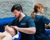 Fizjoterapeuta wykonuje masaż głowy pacjentowi. Studia fizjoterapia ile trwają? To pytanie nurtuje wielu przyszłych specjalistów.