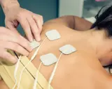 Rehabilitacja TENS: na czym polega? Fizjoterapeuta umieszcza elektrody na plecach pacjentki, co jest częścią terapii prądami TENS.
