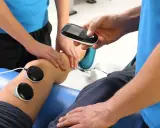 Fizjoterapeuta z urządzeniem do elektroterapii przy nodze pacjenta. Ile razy w roku można korzystać z rehabilitacji szpitalnej?