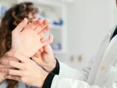 Lekarz bada dłoń pacjenta, podejrzewając reumatyzm.