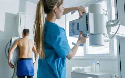 Technik przygotowuje aparat RTG do badania pacjenta. To właśnie RTG co to jest – badanie obrazowe wykorzystujące promieniowanie rentgenowskie.