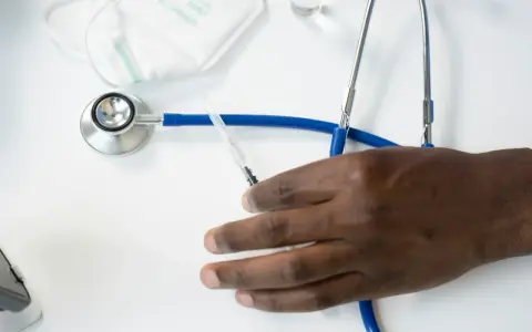 Dłoń pacjenta obok stetoskopu i strzykawki. Czy fizjoterapeuta wystawia L4?