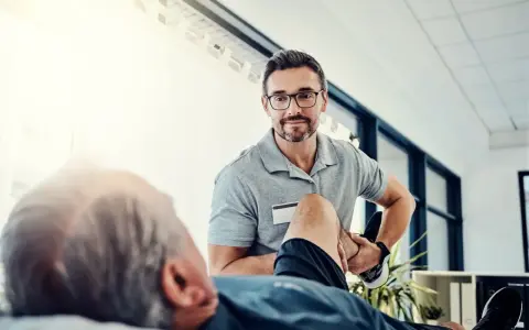 Fizjoterapeuta pomaga pacjentowi w ćwiczeniach rehabilitacyjnych, by odzyskać sprawność.