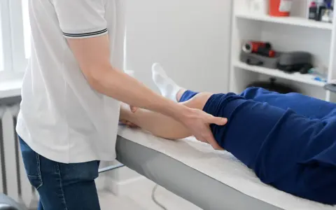 Fizjoterapeuta wykonuje zabieg na nodze pacjenta. Fizjoterapia ambulatoryjna co to znaczy? To leczenie poza szpitalem, w przychodni.