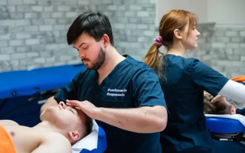 Fizjoterapeuta wykonuje masaż głowy pacjentowi. Studia fizjoterapia ile trwają? To pytanie nurtuje wielu przyszłych specjalistów.