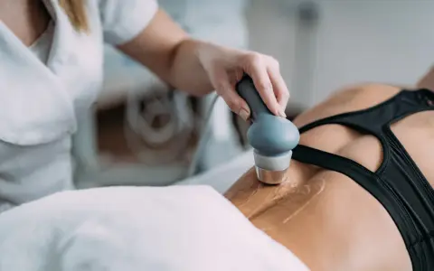 Fizjoterapeuta stosuje głowicę do terapii ultradźwiękami na plecy pacjentki, wspomagając regenerację.