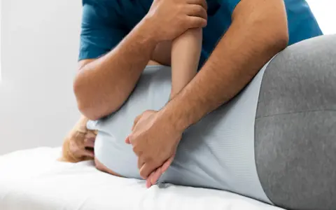 Fizjoterapeuta wykonuje masaż pleców. Czy fizjoterapia może zaszkodzić? Zawsze wybieraj doświadczonych specjalistów.