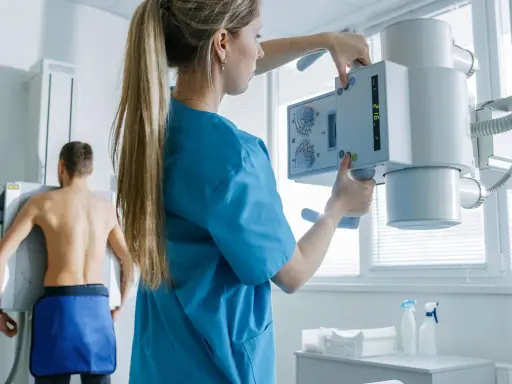 Technik przygotowuje aparat RTG do badania pacjenta. To właśnie RTG co to jest – badanie obrazowe wykorzystujące promieniowanie rentgenowskie.