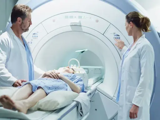 Pacjentka leży w aparacie do rezonansu magnetycznego, a lekarze przygotowują badanie z kontrastem.
