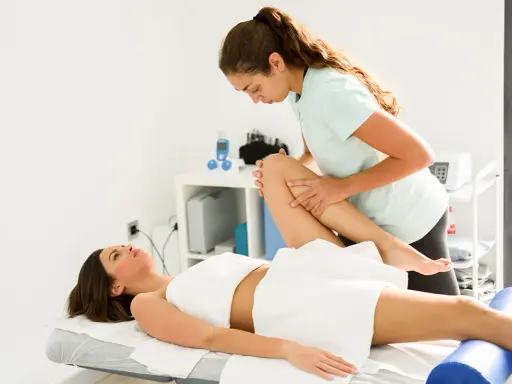 Fizjoterapeuta wykonuje ćwiczenia z pacjentką. Czy fizjoterapeuta a rehabilitant to to samo? W gabinecie fizjoterapii.