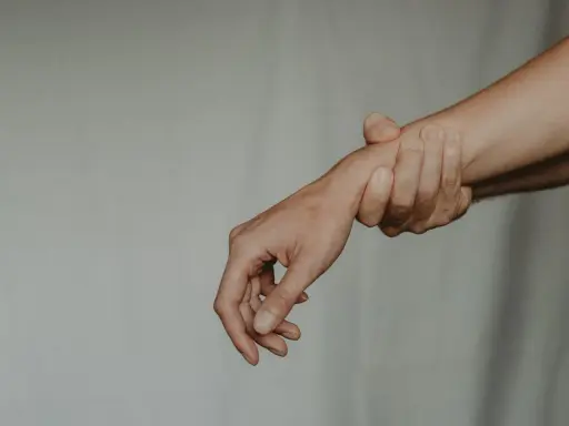 Dłoń trzymająca nadgarstek, symbolizująca ból i pytanie: kiedy zacząć rehabilitacja po operacji cieśni nadgarstka?