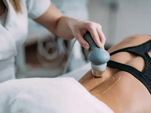 Rehabilitacja ultradźwięki na czym polega? Fizjoterapeuta wykonuje zabieg ultradźwiękami na plecach pacjentki, co pomaga w leczeniu bólu i regeneracji tkanek.