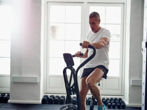 Mężczyzna ćwiczy na rowerze stacjonarnym, który może być dobrym wyborem, jeśli zastanawiasz się, jaki rower stacjonarny do rehabilitacji wybrać.