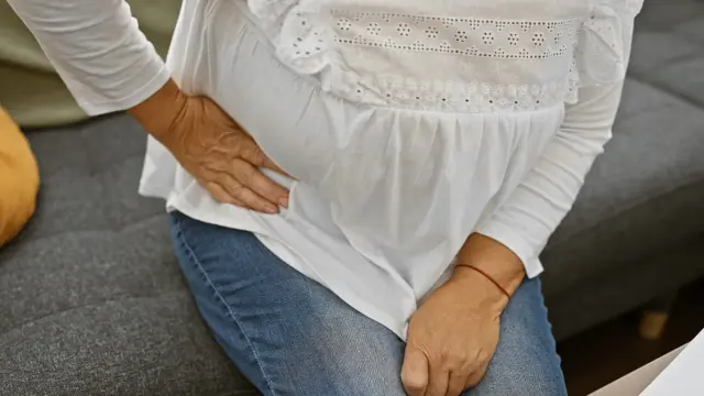 Kobieta z ręką na biodrze szuka domowych sposobów na ból biodra.