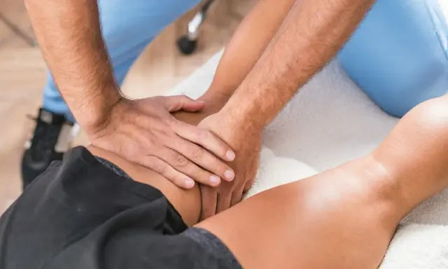 Fizjoterapeuta masuje udo pacjenta. Zastanawiasz się, ile godzin trwa etat fizjoterapeuty?