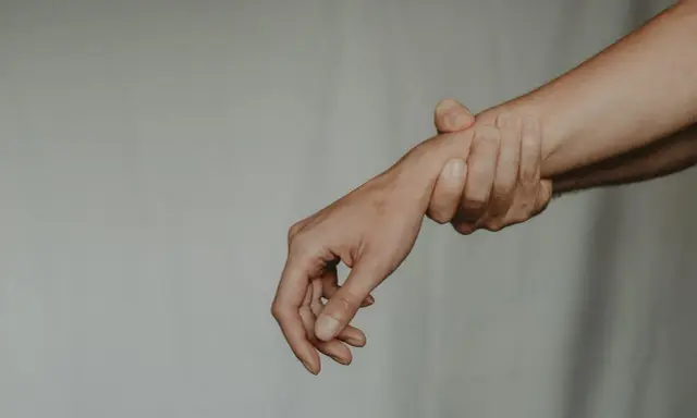 Dłoń trzymająca nadgarstek, symbolizująca ból i pytanie: kiedy zacząć rehabilitacja po operacji cieśni nadgarstka?