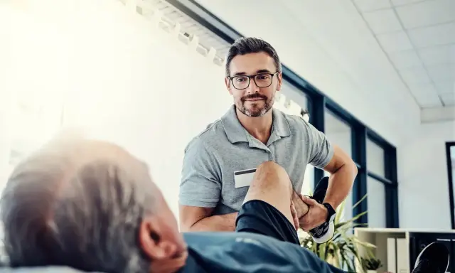 Fizjoterapeuta pomaga pacjentowi w ćwiczeniach rehabilitacyjnych, by odzyskać sprawność.
