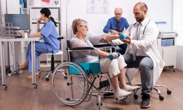 Rehabilitacja po udarze w szpitalu: starsza pani ćwiczy z fizjoterapeutą, by odzyskać sprawność.