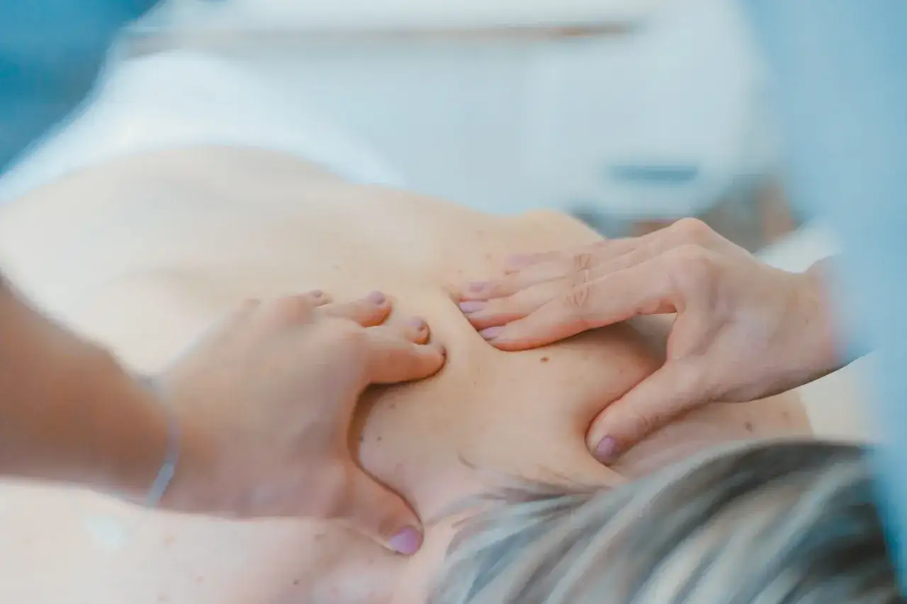 Fizjoterapeuta wykonuje masaż pleców, pomagając rozluźnić napięte mięśnie.