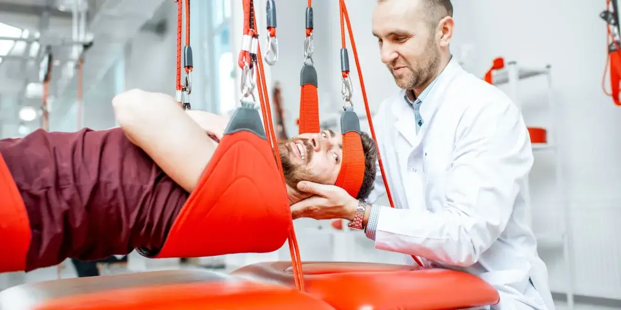 Fizjoterapeuta pomaga pacjentowi w rehabilitacji szyi za pomocą specjalistycznego sprzętu.