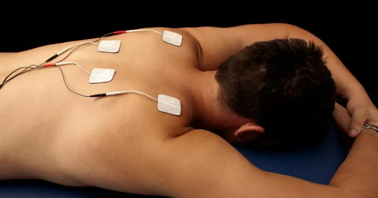 Rehabilitacja TENS: elektrody na plecach pacjenta. Ta metoda polega na stymulacji nerwów prądem.