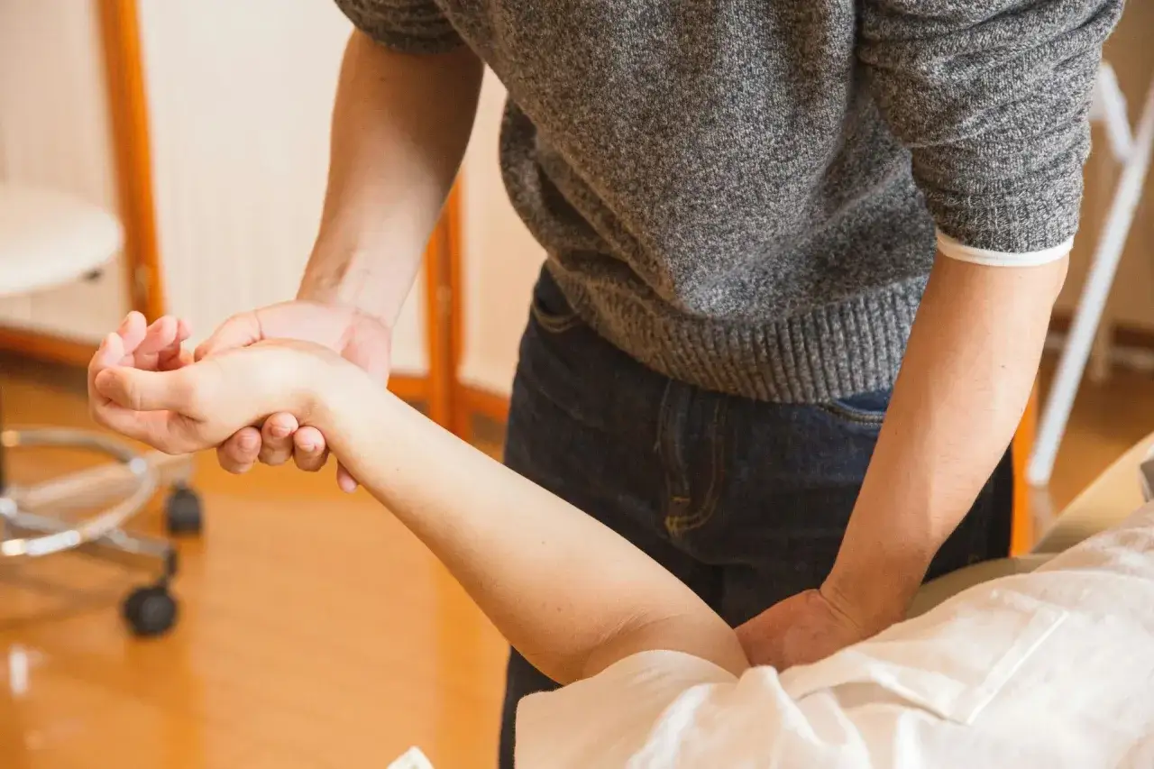 Fizjoterapeuta pomaga pacjentowi w ćwiczeniach, które mogą przyspieszyć powrót do zdrowia po złamaniu ręki.