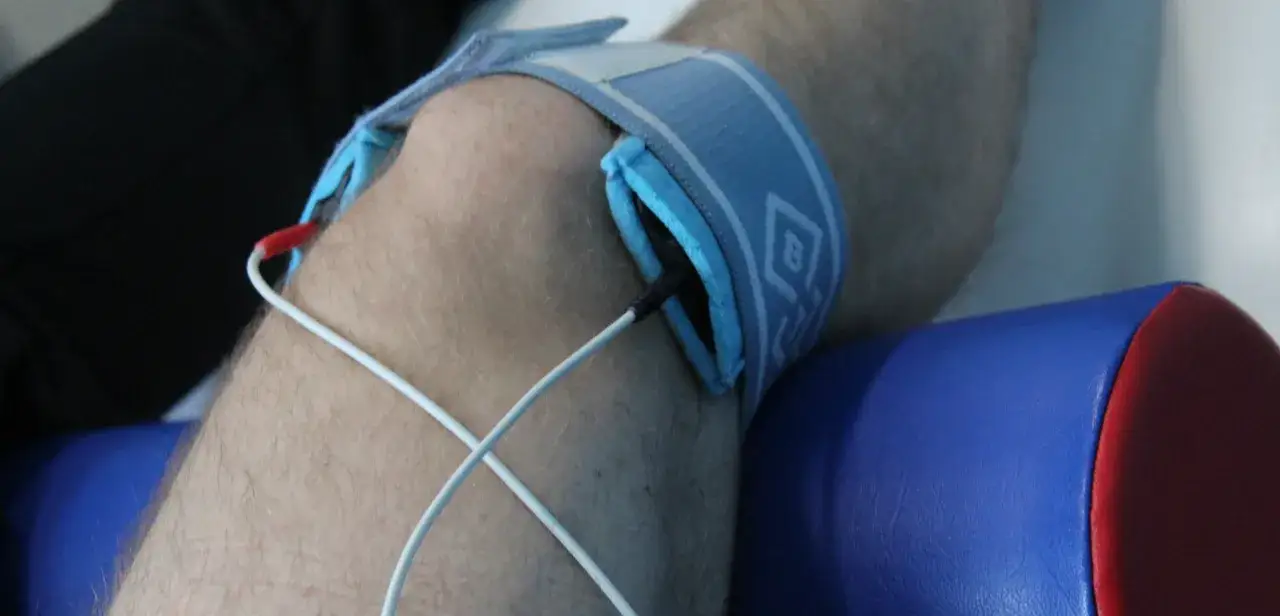 Elektrostymulacja podczas rehabilitacji po endoprotezie kolana. Elektrody podłączone do opaski na nodze.