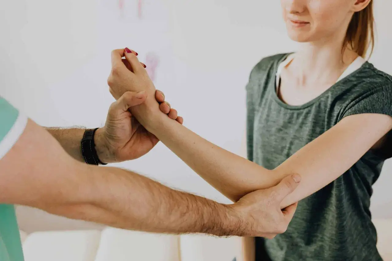 Fizjoterapeuta bada rękę pacjentki. Długość rehabilitacji po złamaniu zależy od wielu czynników.