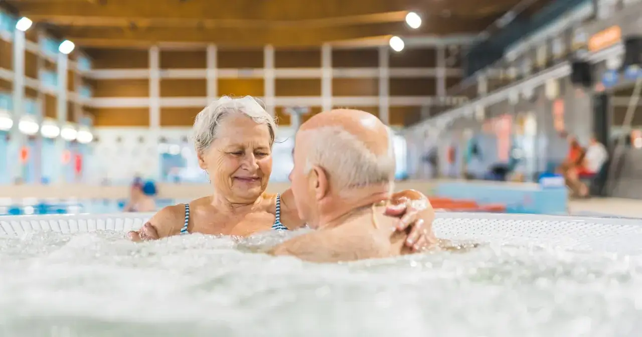 Uśmiechnięta para seniorów w jacuzzi. Nowe zasady wyjazdu do sanatorium na NFZ sprawiają, że więcej osób może cieszyć się relaksem i zdrowiem.
